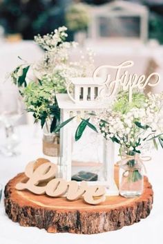 a centerpiece with flowers and greenery on a wooden slice at a wedding reception