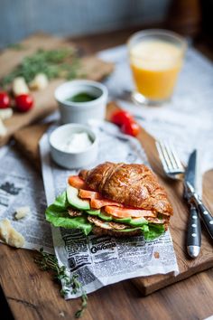 a sandwich with meat, lettuce and tomato on it sitting on a cutting board