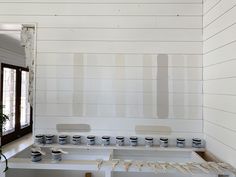 some paint cans are sitting on a shelf in front of a wall that has been painted white