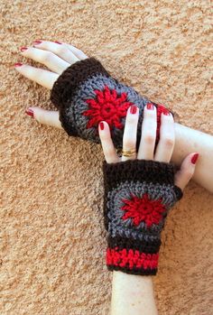 a woman's hand with red and black crocheted fingerless gloves on