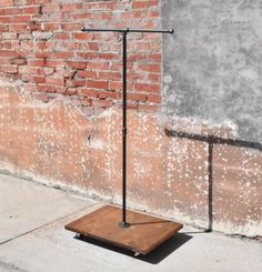 a wooden table sitting on the side of a road next to a brick wall with an umbrella over it