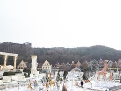 people are walking around in the snow near some buildings and giraffes on display