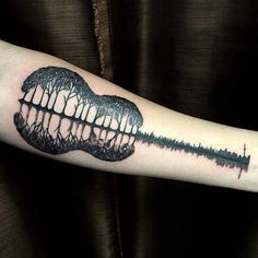 a person with a tattoo on their arm that has trees in the shape of a guitar