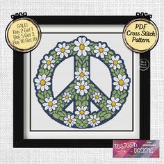 a cross stitch peace sign with daisies on it