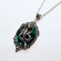 a necklace with a snake in the center and green glass on it's side