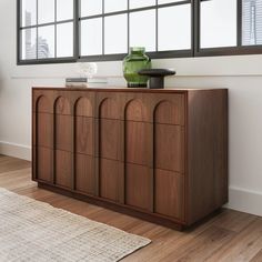 a wooden cabinet sitting in front of a window next to a rug on top of a hard wood floor