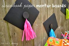 two black graduation caps with tassels hanging on the side of a fence that says scrapbook paper mortar boards