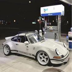 a white porsche parked in front of a gas station