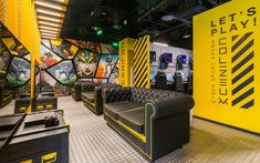 the inside of a gaming room with couches, tables and video game equipment on display