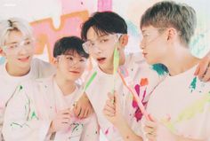 four boys with glasses and paint on their faces are posing for the camera in front of a colorful wall