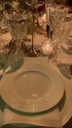 the table is set with clear glassware and candlesticks for an elegant dinner