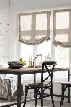 a dining room table with two chairs next to it and some blinds on the windows