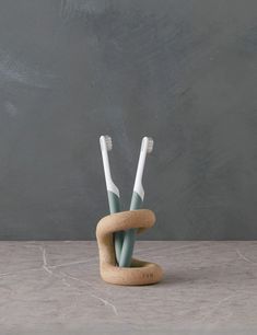 two toothbrushes sitting in a holder made out of cork on a marble surface