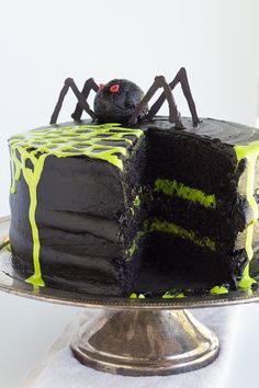 a chocolate cake with green icing and a spider on the top is sitting on a silver platter