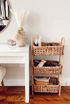 a white table with baskets on it next to a mirror and other items in the room