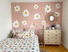 a bedroom with pink walls and white flowers on the wall