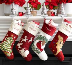 christmas stockings hanging from a mantel with poinsettis