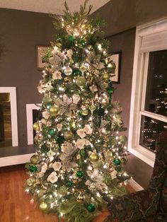 a decorated christmas tree in the corner of a living room with green and white ornaments