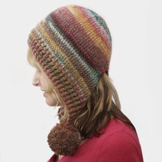 a woman wearing a multicolored knit hat with a pom - pom