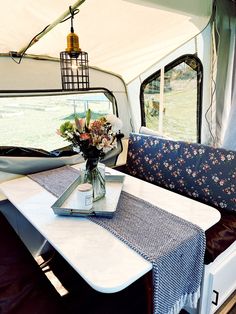 a table with flowers in a vase on it next to a camper door and window