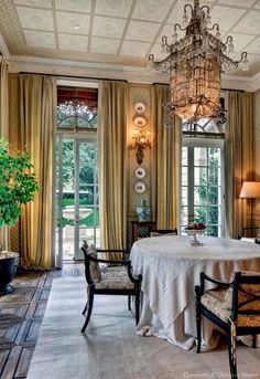 an elegant dining room with chandelier and table set for four in front of large windows