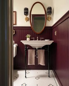 a white sink sitting under a mirror in a bathroom next to a wooden framed mirror