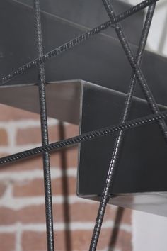 a close up of a metal structure near a brick wall