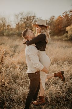 a pregnant woman is holding her husband in the middle of a field