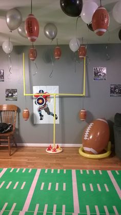 a sports themed room with balloons and footballs hanging from the ceiling, along with other decorations