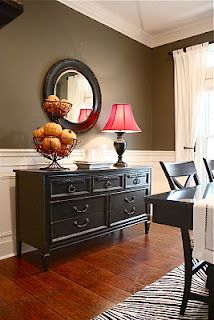 a dining room table with chairs and a mirror on the wall above it, along with a black dresser