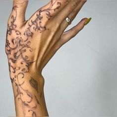 a woman's hand with tattoos on it and yellow nail polish varnishing