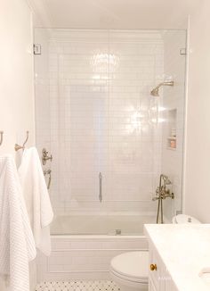 a bathroom with white tile and black and white flooring