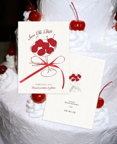 a white cake with cherries on top and a red ribbon