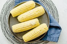 grilled corn on the cob in a bowl with a blue napkin next to it