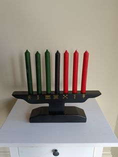 a hanukkah with seven candles sitting on top of a white dresser next to a wall