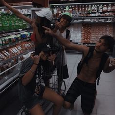 three people standing in front of a grocery cart with their arms out and pointing at something