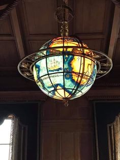 a light fixture hanging from the ceiling in a room with wood paneling and windows