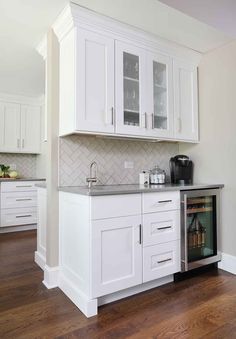 a kitchen with white cabinets and wood floors