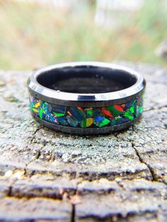 "Quick note: It was raining when I took these pictures but I didn't have time to wait for the weather to cooperate. The little droplets you see on the ring are just water, not imperfections. This beautiful, black ceramic ring features large chunks of black fire opal that have been thoughtfully arranged, one at a time, around the ring. The colors in this fire opal are hard to describe so I have included several pictures. As the light hits the opal at different angles, the colors shift and change Black Multi-stone Wedding Rings, Black Multi-stone Wedding Jewelry, Black Multi-stone Anniversary Rings, Black Multi-stone Rings For Anniversary, Ceramic Wedding, Black Fire Opal, Ceramic Ring, Types Of Opals, Fire Opal Ring