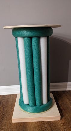 a green and white vase sitting on top of a wooden stand next to a wall