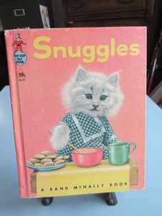 an old children's book with a cat sitting at a table in front of it