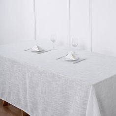 the table is set for two with place settings on it and empty wine glasses in front