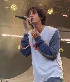 a man standing on top of a stage holding a microphone in his hand and singing