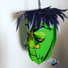 a green mask hanging from a hook on a wall