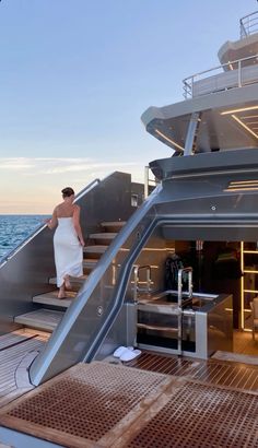 a woman in a white towel is walking up stairs on a boat that's docked at sea