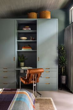 a bedroom with blue cabinets and a leather chair