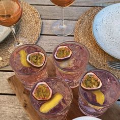 three glasses filled with wine sitting on top of a wooden table next to plates and utensils