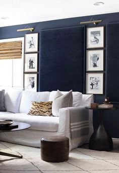 a living room with blue walls and pictures on the wall above the white couches