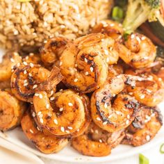 a plate with shrimp, broccoli and sesame seeds on it next to rice