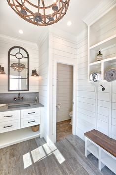 a bathroom with white walls and wood flooring has a chandelier hanging from the ceiling